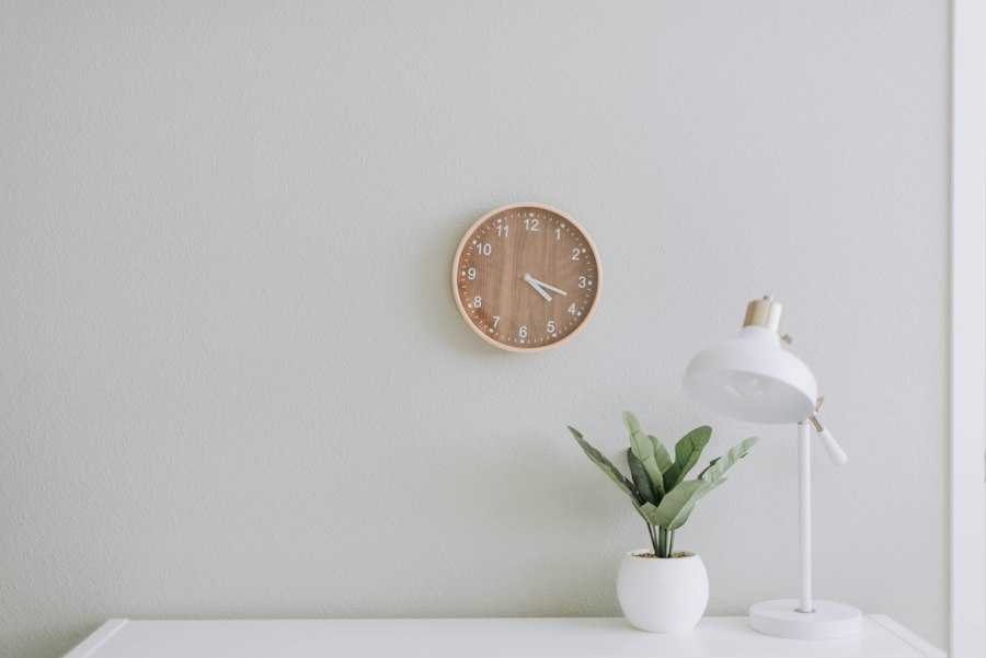 A minimal interior wall with a round clock and a small sideboard