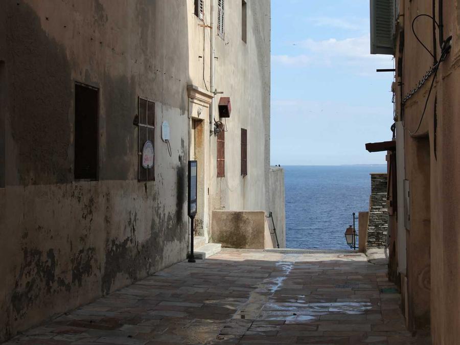 A narrow old-town passage opening onto the sea at the far end