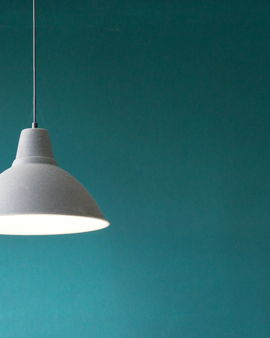 Orbet pendant lamp in brushed steel against a teal wall